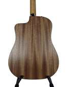 The back of an acoustic-electric guitar with a rich brown wood grain finish, resting on a black stand against a light gray background.