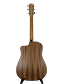 The back view of a wooden acoustic-electric guitar on a black stand, showing a rich brown wood grain finish against a light gray background.