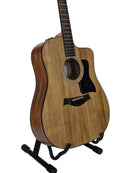 An acoustic-electric guitar with a natural wood body and dark pickguard, displayed on a black stand against a light gray background.