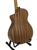 The back of a wooden acoustic-electric guitar with a glossy mahogany finish, displayed on a black stand against a light gray background.