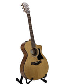 An acoustic-electric guitar with a natural wood finish and black pickguard, displayed on a stand against a light gray background.