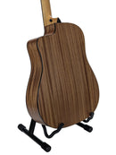 The back of an acoustic guitar with a rich brown wood grain finish, displayed on a black stand against a clean white background.