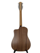 A 12-string acoustic-electric guitar shown from the back, featuring a dark wood grain body and a natural wood neck, displayed on a stand against a light gray background.
