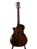 The back of a dark wood acoustic guitar with a glossy finish, standing on a black display stand against a light gray background.