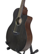 A dark wood acoustic guitar with a cutaway body and dark fingerboard, displayed on a black stand against a white studio background.