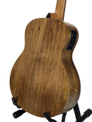 The back of a wooden acoustic-electric guitar resting on a black stand against a white studio background.
