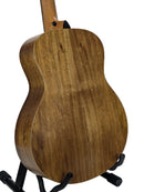 The back of a wooden acoustic guitar on a black stand, showing a natural medium-brown wood grain finish against a light gray background.
