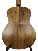 The back of a wooden acoustic guitar, showing a natural medium-brown wood grain finish, displayed on a black stand against a light gray background.