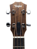 Close-up of a Taylor guitar headstock with four tuning pegs, four strings, and the Taylor logo on a light gray background.