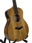 A natural wood acoustic-electric guitar with a black pickup and stand, photographed against a light gray background.